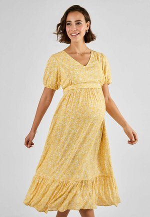 Yellow floral maternity dress with short puff sleeves, V-neckline, gathered waist, and a tiered, ruffled hem, made from lightweight fabric.