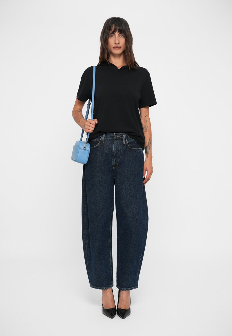 Black polo shirt, wide-legged dark blue jeans, black high heels, and a small light blue crossbody bag. Simple design, no patterns.
