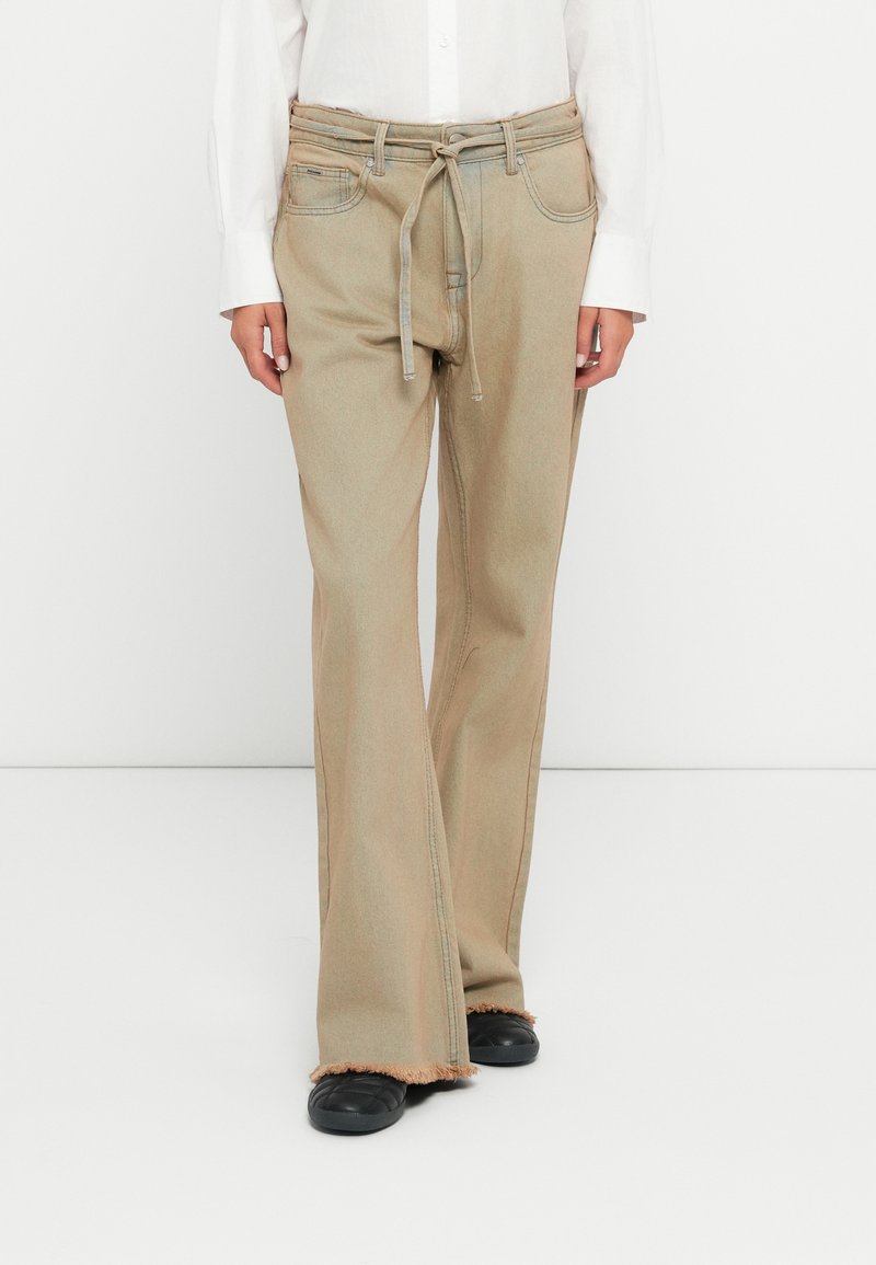 Τα παντελόνια με φαρδιά γραμμή σε καφετί απόχρωση, με ψηλή μέση, διαθέτουν ζωνάκι που δένει, πλαϊνές τσέπες και ακατέργαστο στρίφωμα. Είναι κατασκευασμένα από ανθεκτικό denim ύφασμα.