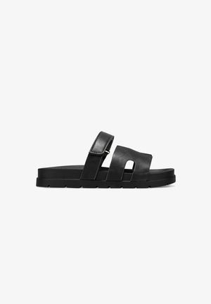 Sandali slide in pelle nera con due cinturini larghi, una texture liscia e una suola spessa. Presentano un design a taglio sulla cinghia per la ventilazione.