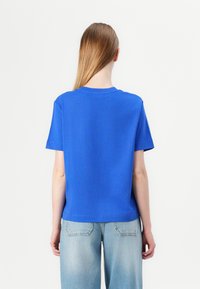 Blå kortärmad t-shirt med rund halsringning, tillverkad av bomull, med en avslappnad passform och en ren, sömlös baksidedesign.