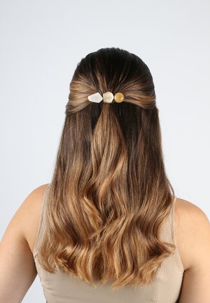 Accessorio per capelli con tre pietre naturali (bianca, beige chiaro, ambra) incastonate in una forcina minimalista, che tiene i capelli mossi in uno stile mezzo su.