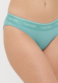 Teal Calvin Klein truser med en myk, elastisk midjebånd som har merkenavnet i hvitt. Glatt tekstur og lav skjæring.