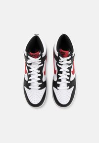 Une paire de baskets montantes Nike noires, blanches et rouges avec des lacets blancs, vue de dessus sur un fond blanc.