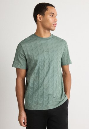 Camiseta corta de manga con textura verde, patrón geométrico, cuello redondo y un logo sutil en el pecho. Tejido suave y transpirable.