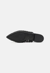 Suela de zapato negra con una superficie texturizada y con patrón. El diseño cuenta con una puntera puntiaguda y una estructura superior trenzada para mayor transpirabilidad.