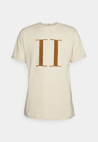 Camiseta de algodón de manga corta color crema con un gran número romano II en marrón impreso en el pecho, cuello redondo y puños de manga enrollados.