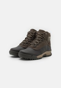 Brown hiking boots made of leather and textile, featuring a padded collar, lace-up design, and rugged rubber outsole for traction.