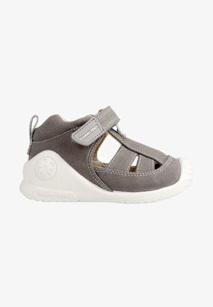 Sandal in tela grigia con design a intaglio, cinturino con chiusura a velcro e suola in gomma bianca. Presenta punta arrotondata e tallone rinforzato.