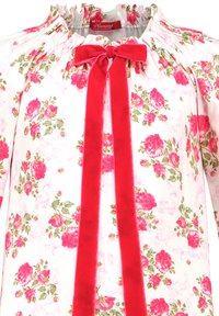 Floral-patterned blouse features a white background with pink roses. Elastic neckline, and a red velvet tie adorns the front.