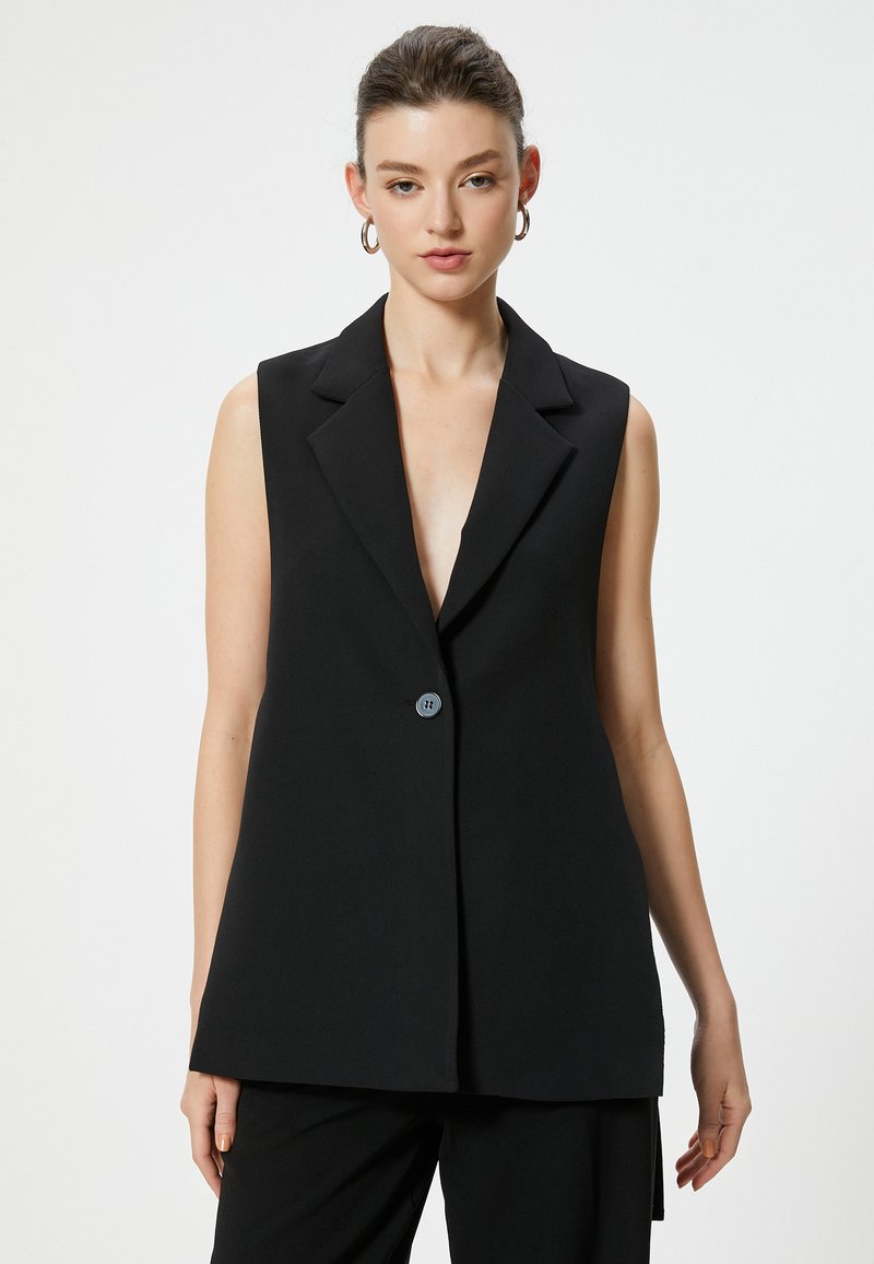 Blazer senza maniche nero con scollatura a V profonda, rever strutturati e chiusura con un solo bottone. Realizzato in un tessuto liscio con finitura opaca.