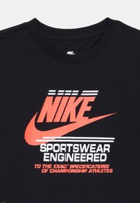 Black cotton t-shirt featuring a prominent red Nike logo and white text. Crew neck design with short sleeves and a smooth texture.