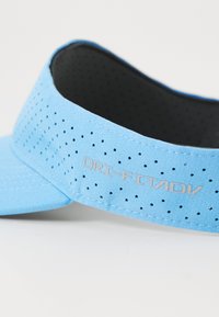 Világoskék napszemüveg, perforált textúrával, DRI-FIT ADV márkajelzéssel ezüst színben, ívelt forma, és sima fekete belső bélés.
