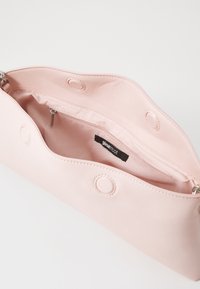 Rosa Kunstledertasche mit glatter Textur, ausgestattet mit einer Innentasche mit Reißverschluss und runden Hardware-Akzenten. Offenes Top-Design.