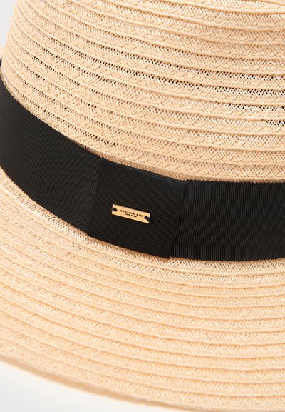 Μπεζ υφαντό ψάθινο καπέλο με φαρδιά μαύρη υφασμάτινη ταινία και μια μικρή χρυσή ορθογώνια ετικέτα στην ταινία.