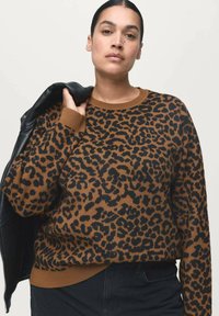 Suéter de estampado de leopardo en tejido marrón y negro, con un escote redondo y puños acanalados. Combinado con una chaqueta de cuero negra.