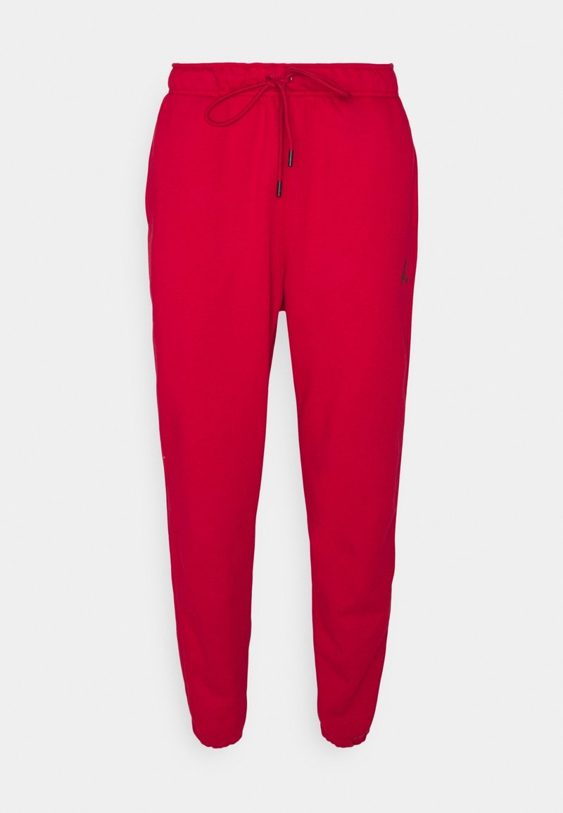 Červené joggingové kalhoty vyrobené z měkké tkaniny, s elastickým pasem na šňůrku, žebrovanými manžetami a malým černým logem na boku.