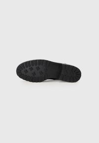 Semelle de chaussure en caoutchouc noir avec des motifs de grip texturés et des accents en forme d'étoile. Design à bords droits, profil plat adapté à diverses surfaces.