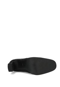 Czarny dzianinowy botek za kostkę z fakturowaną cholewką, zaokrąglonym noskiem i niskim obcasem. Podeszwa jest gładka i płaska, bez widocznych wzorów ani ozdób.