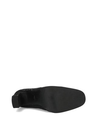 Zwarte gebreide enkellaars met een gestructureerd bovenwerk, afgeronde neus en een lage hak. De zool is glad en vlak zonder zichtbare patronen of accenten.