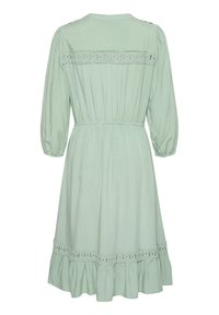 Light green dress with long puff sleeves, cinched waist, and ruffled hem; features lace detailing across the back and lower skirt.