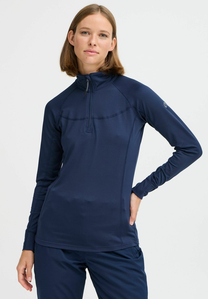 Kék hosszú ujjú pulóver, félig cipzáros gallérral. Simánd, rugalmas anyag, testhez álló szabással. Díszítő varrás a vállaknál és az oldalakon.