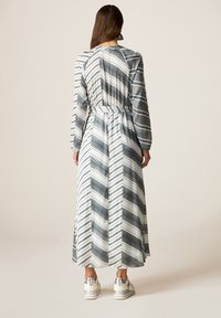 Abito lungo a motivo chevron in grigio e bianco con vita cintrata e maniche lunghe, caratterizzato da un tessuto morbido e una vestibilità rilassata.