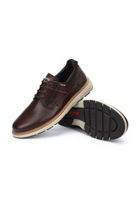 Zapatos de cuero marrón con punta redondeada, diseño con cordones y suela clara en contraste. Presentan detalles texturizados y una suela de goma para mayor agarre.