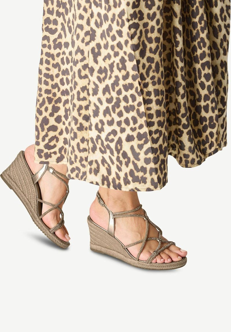 Sandali con tacco a cuneo beige con cinturini luccicanti e suole testurizzate, abbinati a una gonna con stampa leopardata.