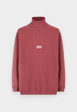 Ljubičasto-siva majica s četvrtastim patentnim zatvaračem, uspravnim ovratnikom, dugim rukavima, rebrastim manžetama i donjim rubom te malim bijelim logom "Kratero Society" u središtu sprijeda.