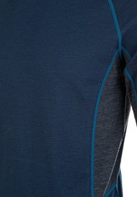 Marinblå sporttröja med en slät textur, kontrasterande grå paneler och turkosa stygn längs sömmarna.
