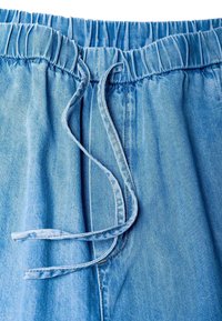 Shorts en jean bleu avec une taille élastique et un cordon de serrage. Texture douce avec des coutures visibles et une coupe décontractée.