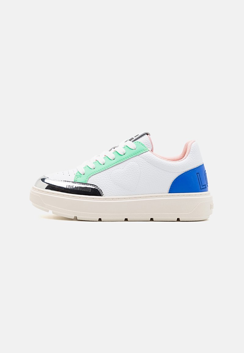 White leather sneakers with green and blue accents, black patent toe, thick cream sole, and textured detailing on the sides.