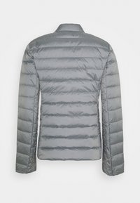 Harmaa puffatakki, kevyt materiaali, tikattu muotoilu, sileä pinta, pitkät hihat, ei näkyvää metalliosaa, takanäkymä esitetty.