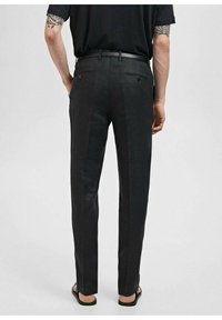 Zwarte broek met een getailleerde pasvorm, een gladde textuur en een subtiel streepjespatroon. Compleet met een riem en zijzakken.
