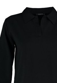 Chemise noire à manches longues avec col et patte courte en V, fabriquée par la marque Trendyol.