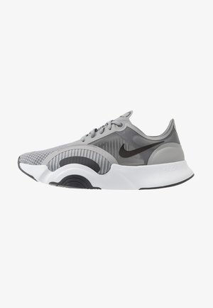 Gray and white Nike running shoe with black swoosh, mesh upper, and thick cushioned Sole designed for comfort and performance.