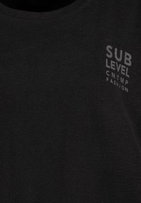 Black fabric with small grey text reading "SUB LEVEL CNTMP FASHION" on the upper chest area.