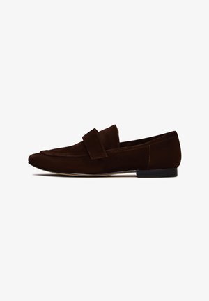 Mocassins en daim marron avec une semelle plate, présentant une large bande sur le dessus pour un maintien sécurisé et une forme élégante et allongée.
