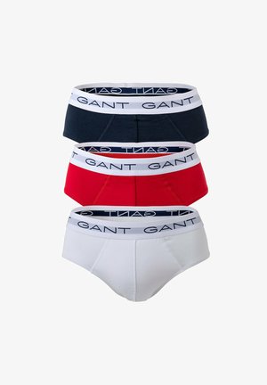 Drei Herren-Slips in Marineblau, Rot und Weiß. Jeder hat einen kontrastierenden Bund mit "GANT"-Logo. Material aus Baumwollmischung.
