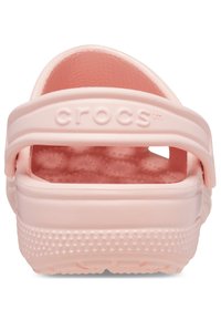 Zuecos rosas de Crocs con un exterior texturizado, correa trasera ajustable y una plantilla acolchada. Presenta pequeños agujeros de drenaje.