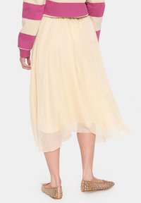 Lichtgele chiffon rok met een asymmetrische zoom, gecombineerd met beige ballerina's met strassteentjes. Gladde textuur, vloeiende uitstraling.