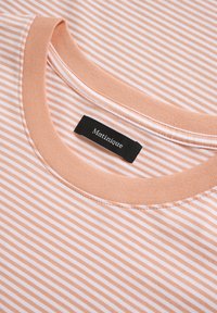 Striped t-shirt in soft peach and white, round neckline with a ribbed collar, featuring a black label with "Matinique" stitched inside.