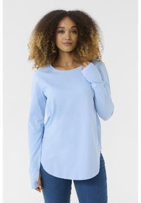 Hellblaues langärmliges T-Shirt aus weichem Stoff, mit rundem Halsausschnitt und leicht geschwungenem Saum, kombiniert mit Denim-Jeans.