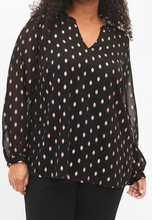 Černá halenka s výstřihem do V, průsvitný materiál a dlouhé rukávy. Vzor se světlými růžovými tečkami po celé ploše. Jednoduché knoflíkové detaily na manžetách.