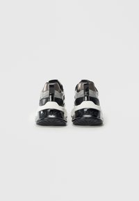Zwarte en zilveren sport sneakers met een witte tussenzool, voorzien van een glanzende afwerking, stevige hak en een gestructureerde rubberen outsole.