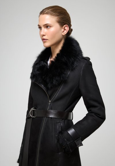 Mustapahuainen takki, jossa on keinokuituinen kaulus, vyötärönauha ja vetoketjusulku. Ominaisuuksiin kuuluu tyylikäs muotoilu ja strukturoidut hihansuut.