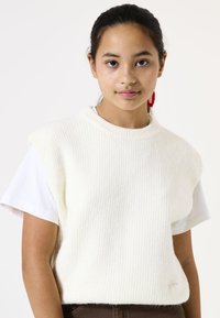 Pull en maille côtelée blanche avec un col rond sur une chemise blanche à manches courtes. Texture remarquable et branding subtil sur l'ourlet.