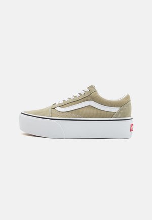 Zapatillas de lona de color oliva claro con detalles en blanco; cuentan con una suela gruesa blanca, punta redonda y la etiqueta del logo clásico de Vans en rojo.