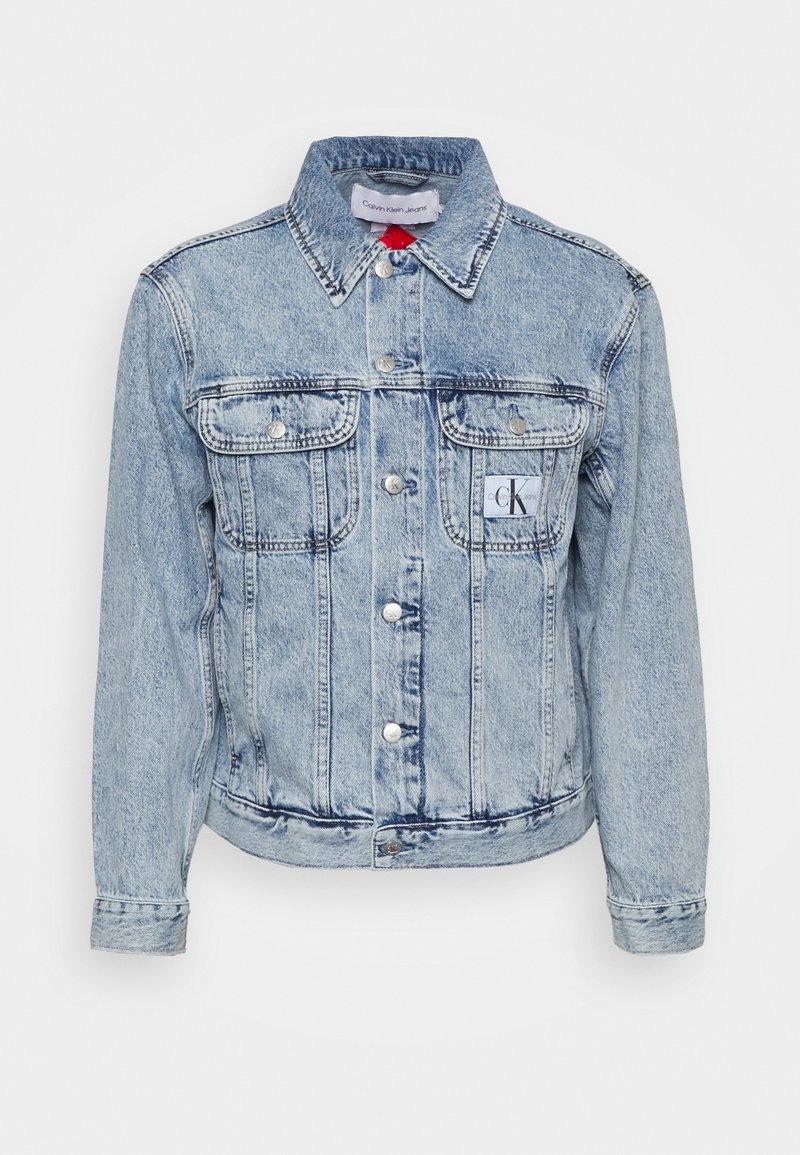 Ljusblå denimjacka med klassisk krage, framknäppning med knappar, två bröstfickor och en liten logotyp på vänster sida.